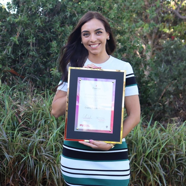 A Banksia Association Honours Scholarship recipient stands holding a certificate