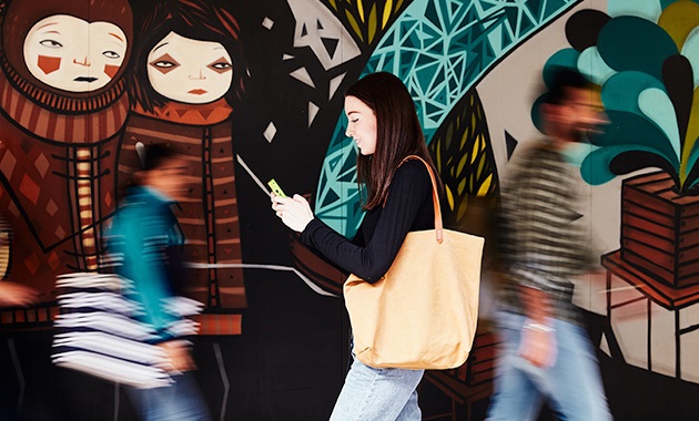 Student walking in front of mural