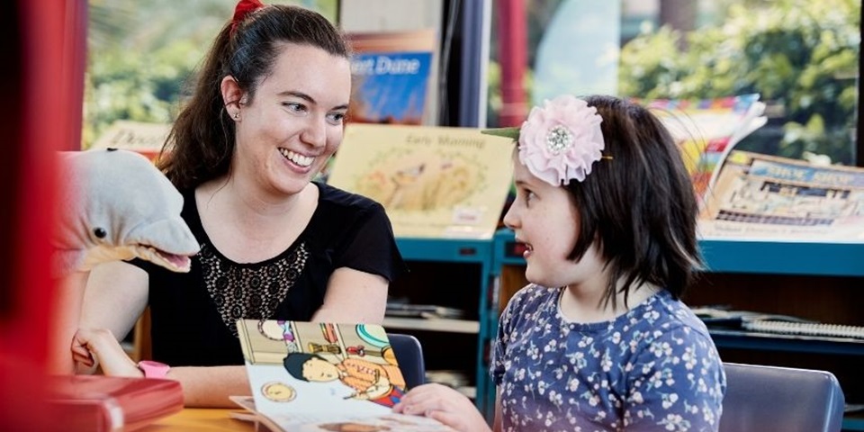 Student reads a book with a child in a classroom