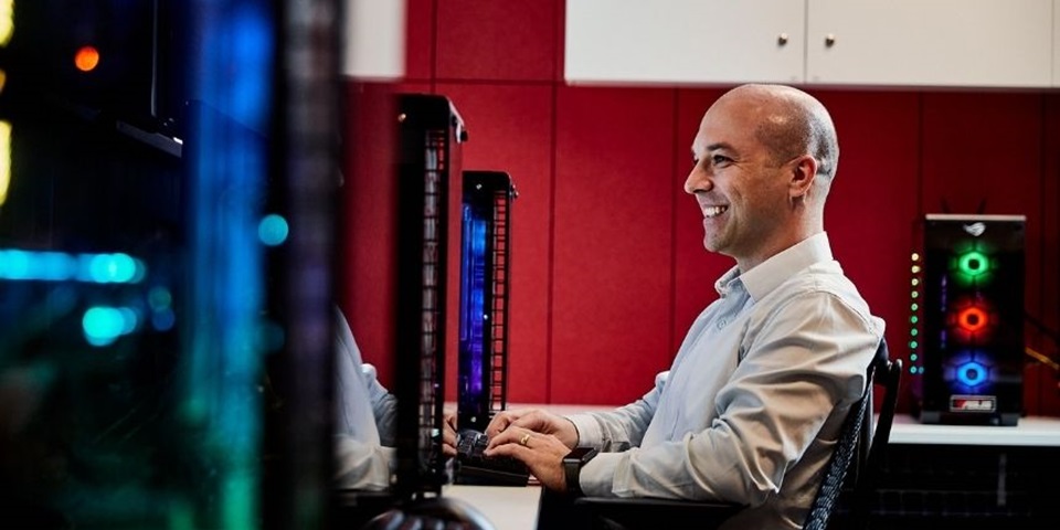 Student sits at computer desk smiling