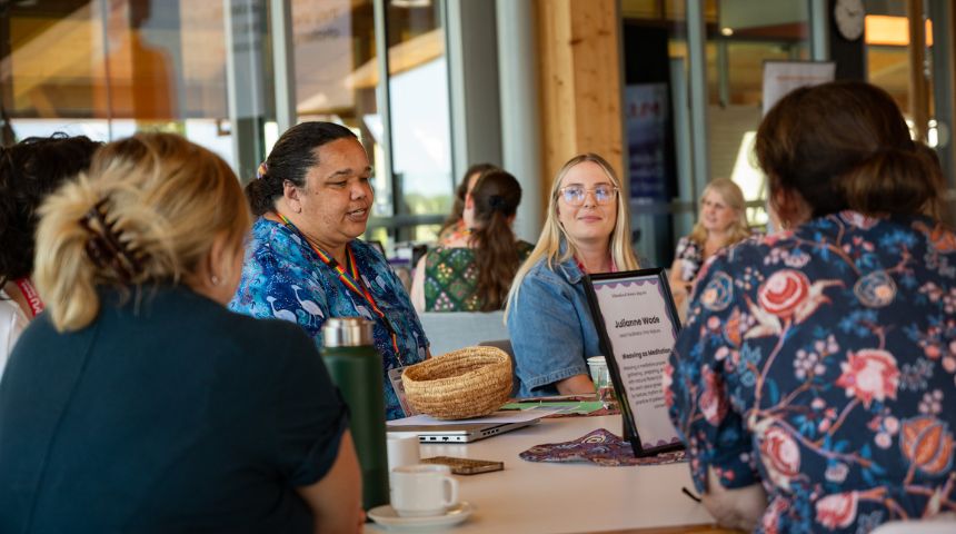 A group of women sitting together at a table, smiling.