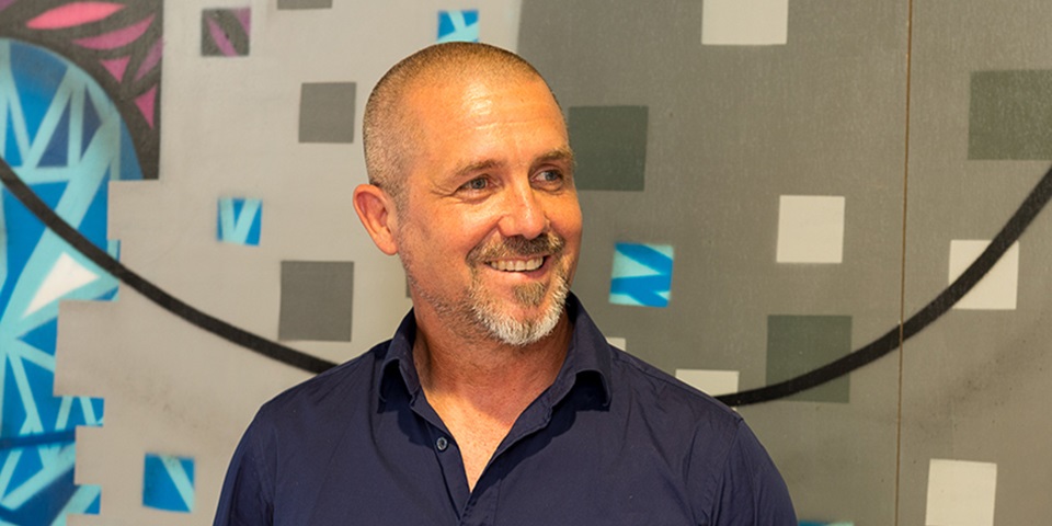 Ian Wilson feature image Academic Ian Wilson smiling to someone off camera with graffiti in background