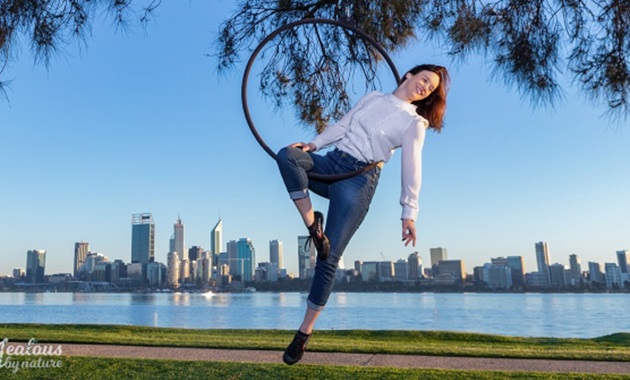 Dr Fleur van Rens balancing on a circus ring with the City of Perth in the background.