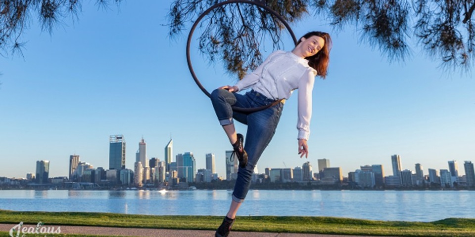 Dr Fleur van Rens balancing on a circus ring with the City of Perth in the background.