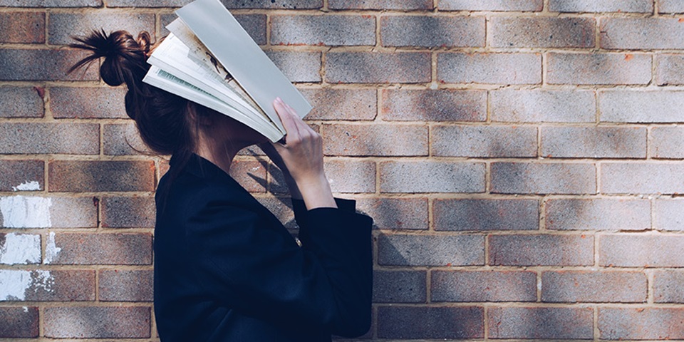 Girl holding book to face feature Girl holding book to face