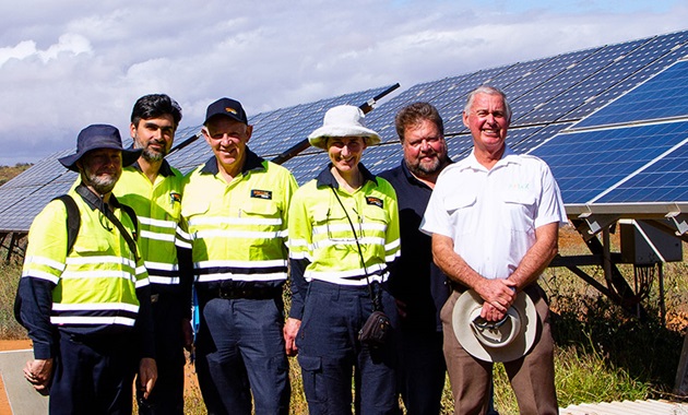 Group of people standing together with solar panels in the background