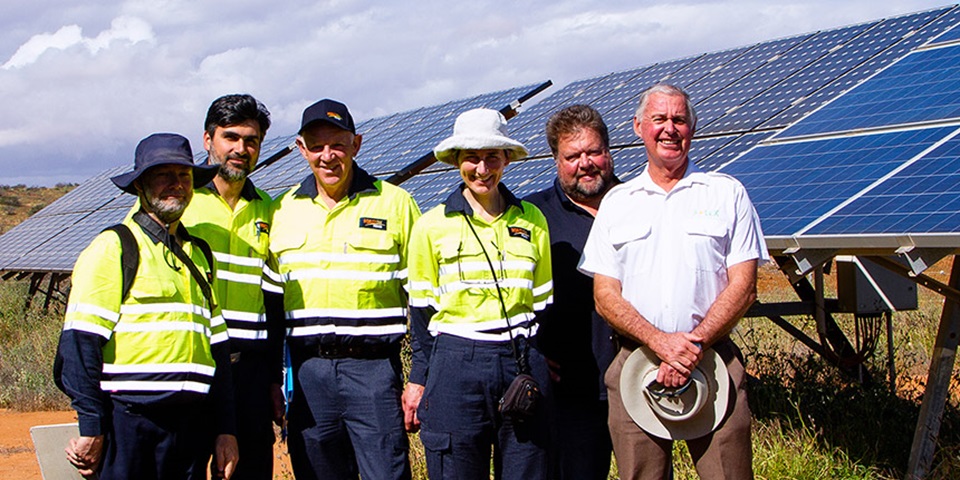 Group of people standing together with solar panels in the background