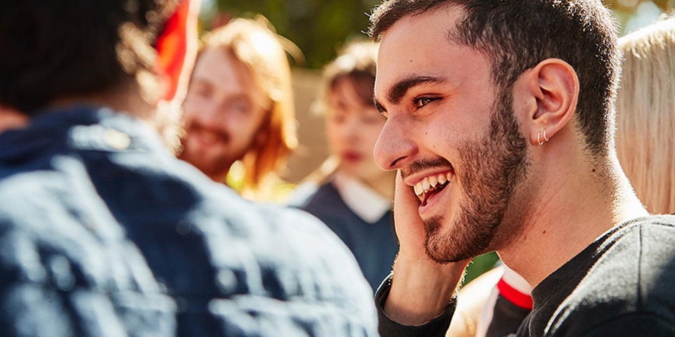 How to fit in at uni feature Student sitting at table with friends and smiling
