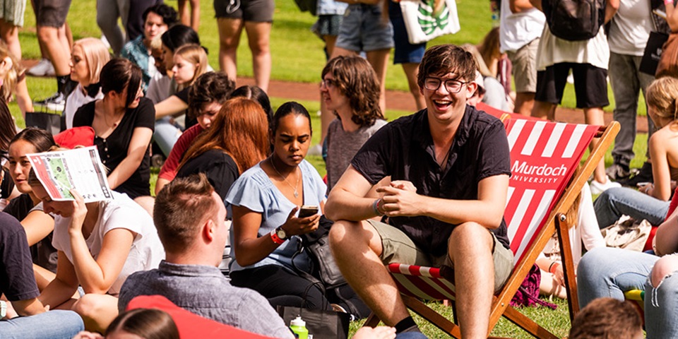 How to make friends feature Image of student sitting on deckchair on Bush Court, smiling to a friend