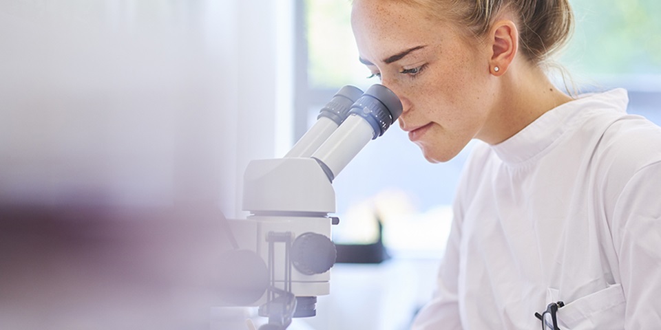 Lab Med Assistant_860x480 Lab Assistant looking through a microscope