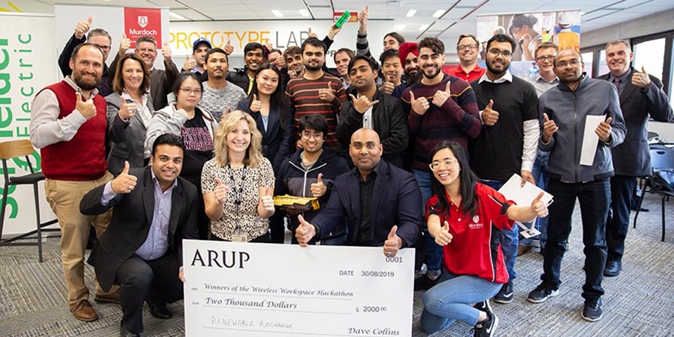 Group of people smiling and holding a big cheque