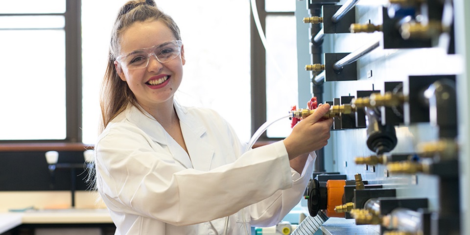 MSCP_Job_Feature Female student smiling next to equipment.