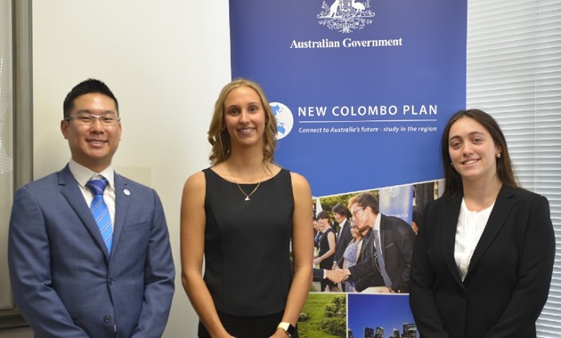 Three Murdoch students, recipients of the New Colombo Plan (NCP) Scholarship, stand in front of NCP banner