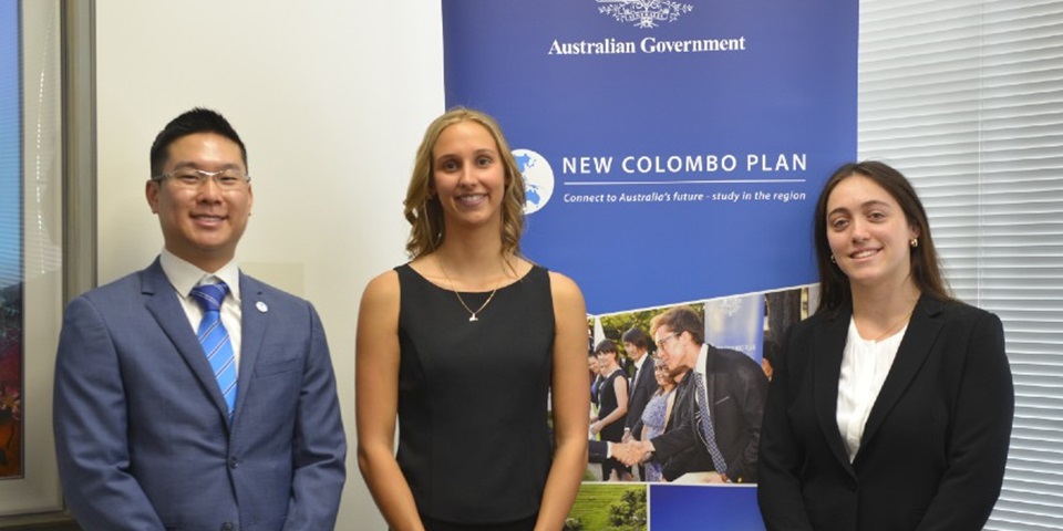 Three Murdoch students, recipients of the New Colombo Plan (NCP) Scholarship, stand in front of NCP banner