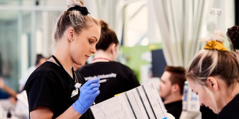 Nursing - Feature Female nursing looking at patients file