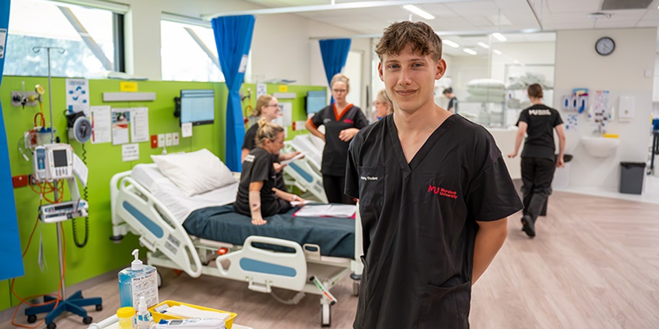 Nursing_Study_Feature Male student stands in front of class in the SimLab.