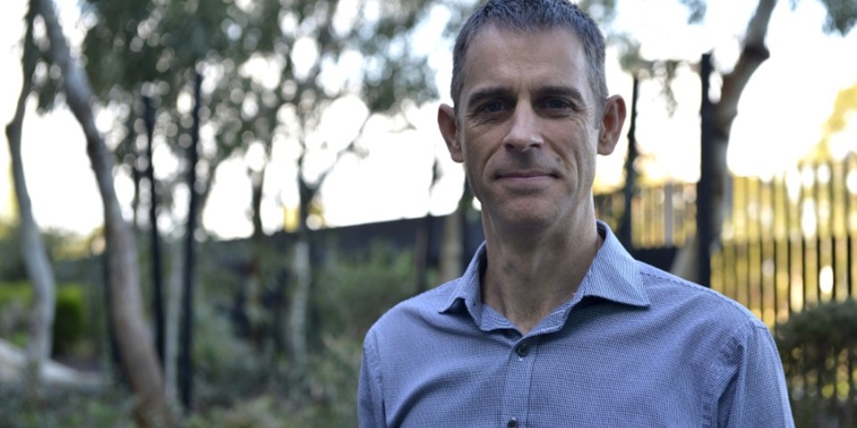 Dr Owen Robinson standing by some trees