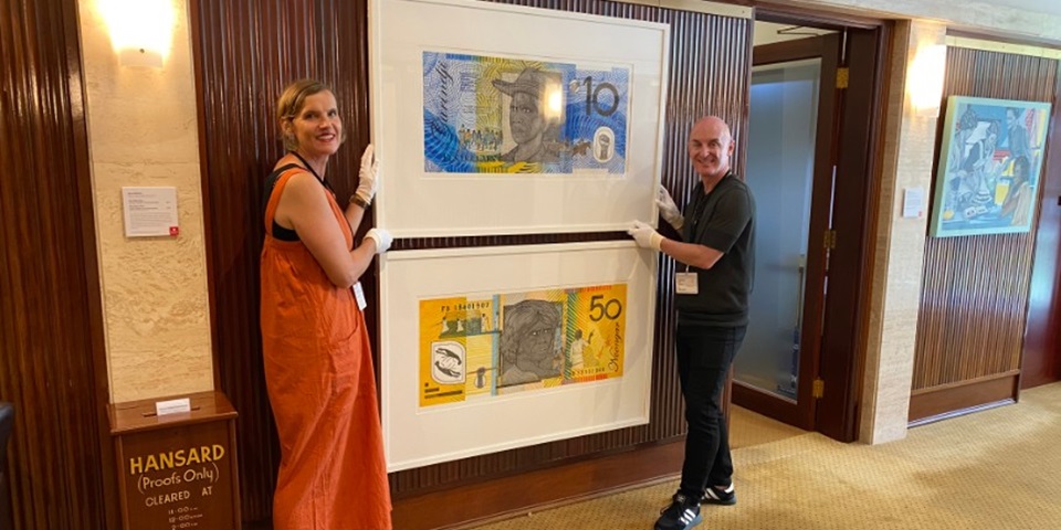 Murdoch curators Mark Stewart & Jane Chambers installing artworks resembling money by Ryan Presley