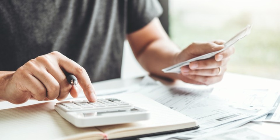 Person using a calculator, whilst holding a pen