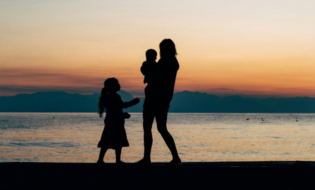 A family standing silhouetted on a beach.