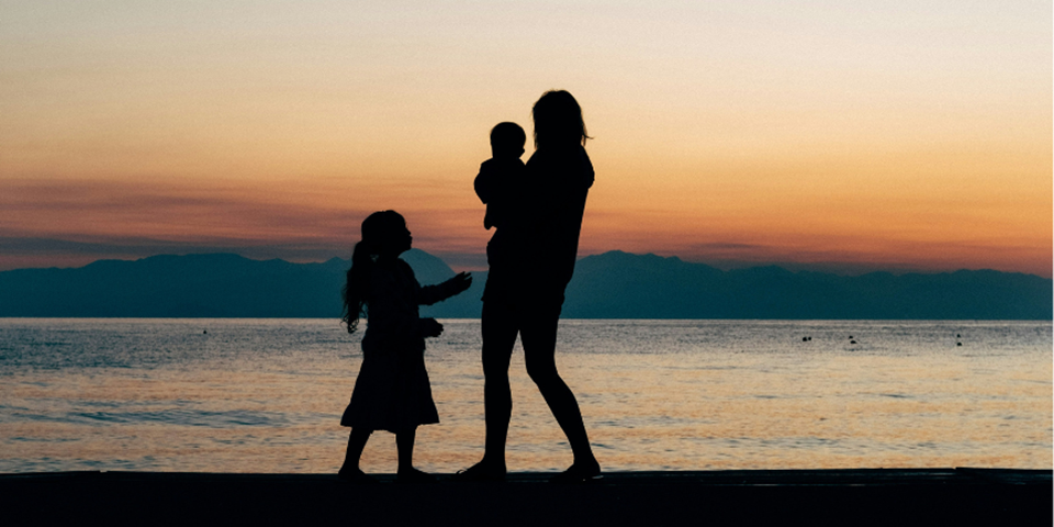 A family standing silhouetted on a beach.