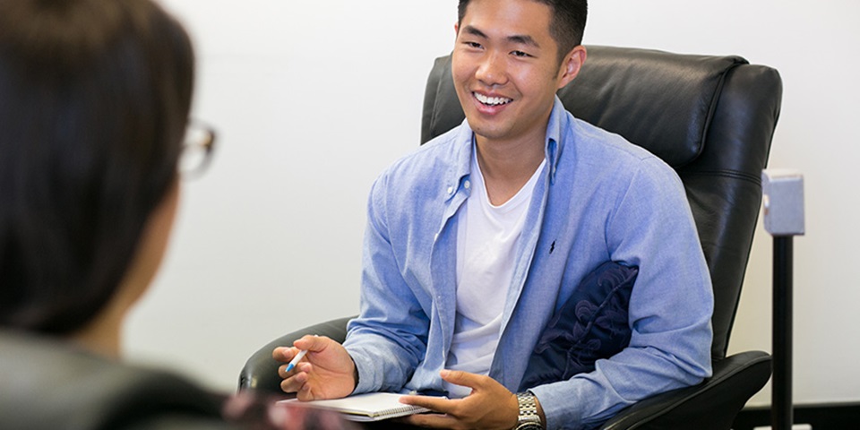 Psychology_Career_Feature Male student in a therapy session, smiling.
