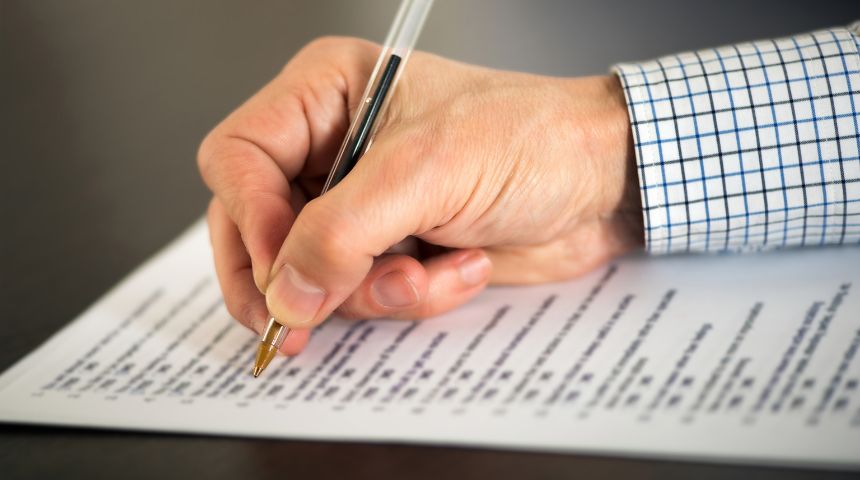 A hand holding a pen, completing a questionnaire