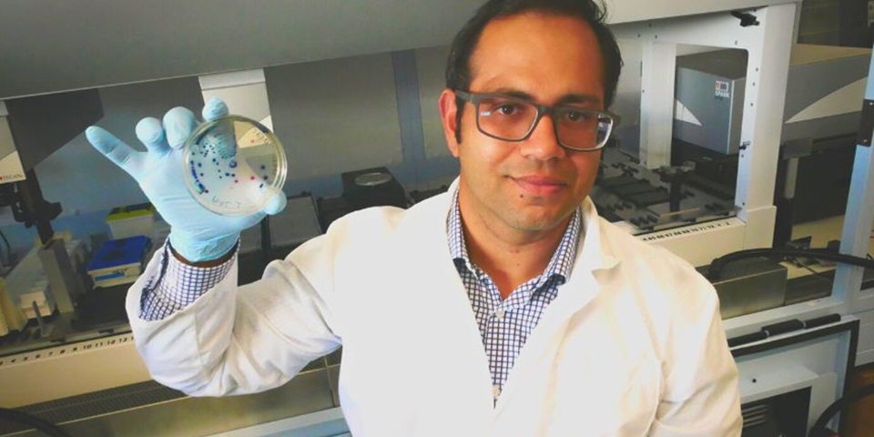 Sam Abraham holding petri dish in a lab