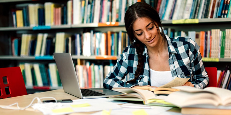 Student studying in the library on her laptop