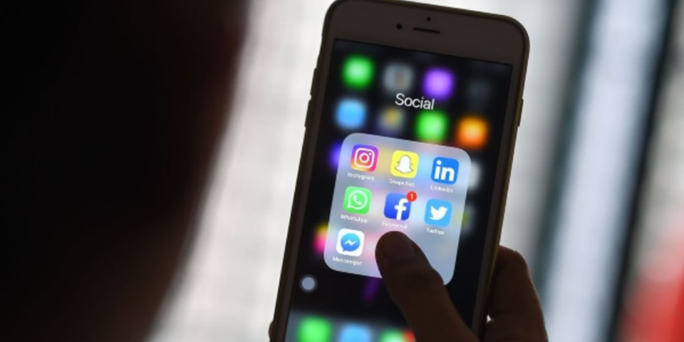Person holding a smartphone showing social media apps.