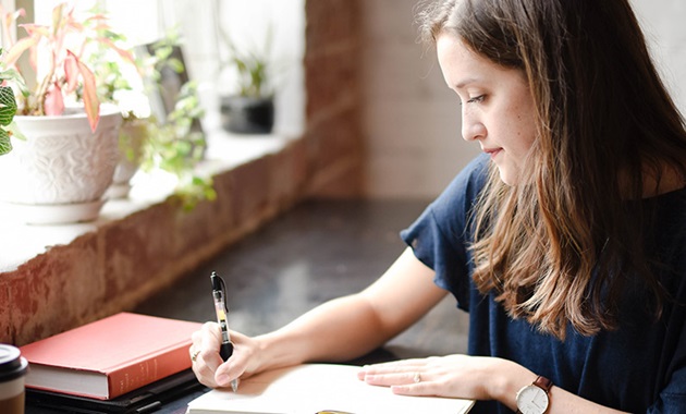 Girl studying and writing notes in a cafe