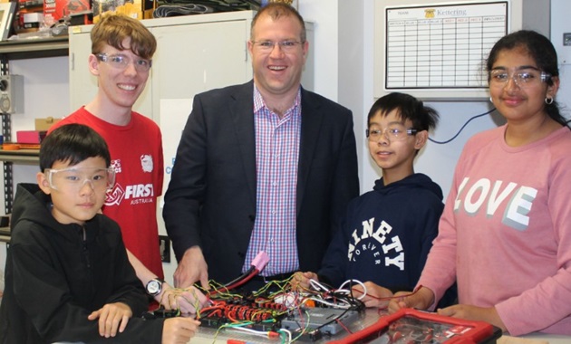 Students with Ben Morton building a robot at a table