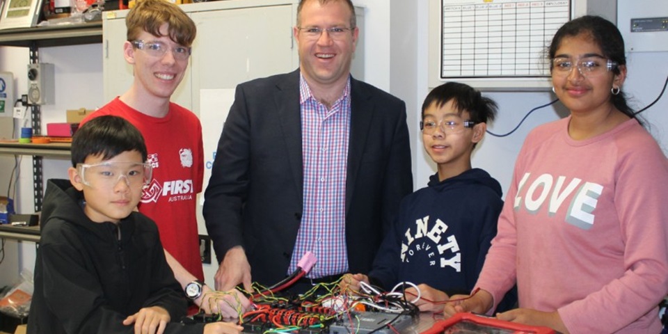 Students with Ben Morton building a robot at a table