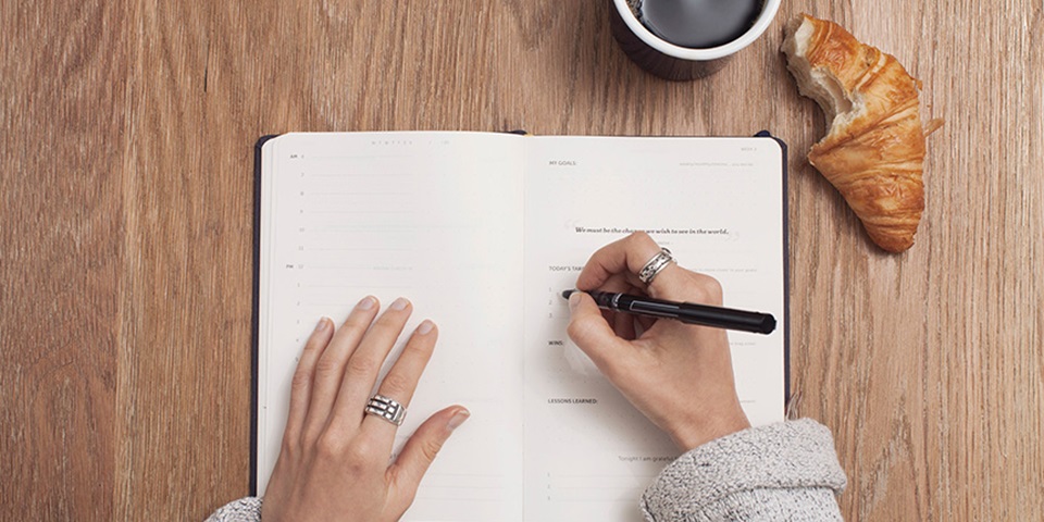 Top view of person writing in diary at desk feature Top view of person writing in diary at desk