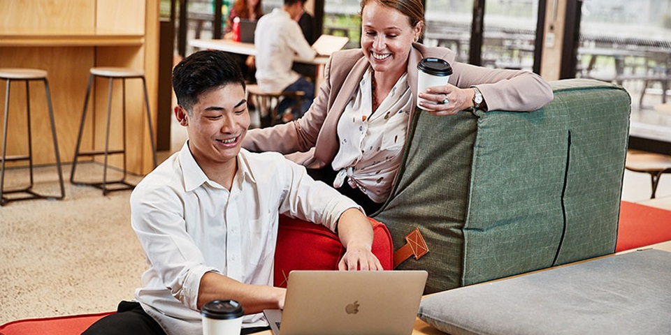 Two business students working together at a cafe Students smiling as they collaborate on a laptop