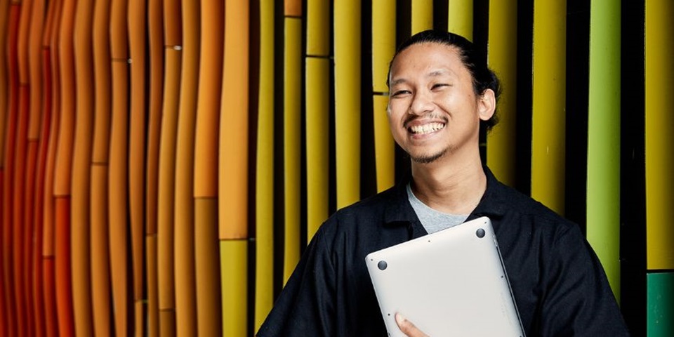 What is an MBA Feature Murdoch student smiling off camera holding a laptop.